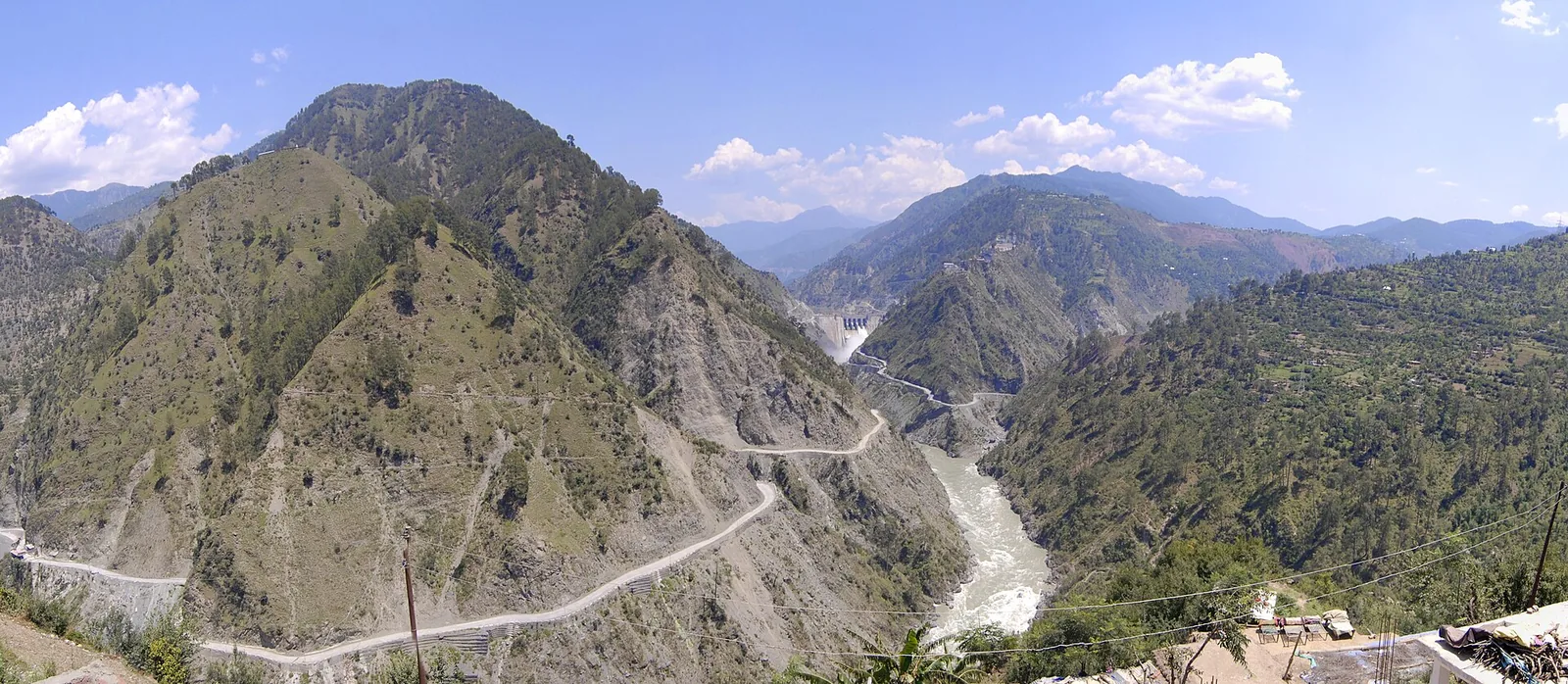 A wide photograph of the Baglihar hydroelectric dam on the Chenab river in Jammu and Kashmir, set in a steep brown gorge.