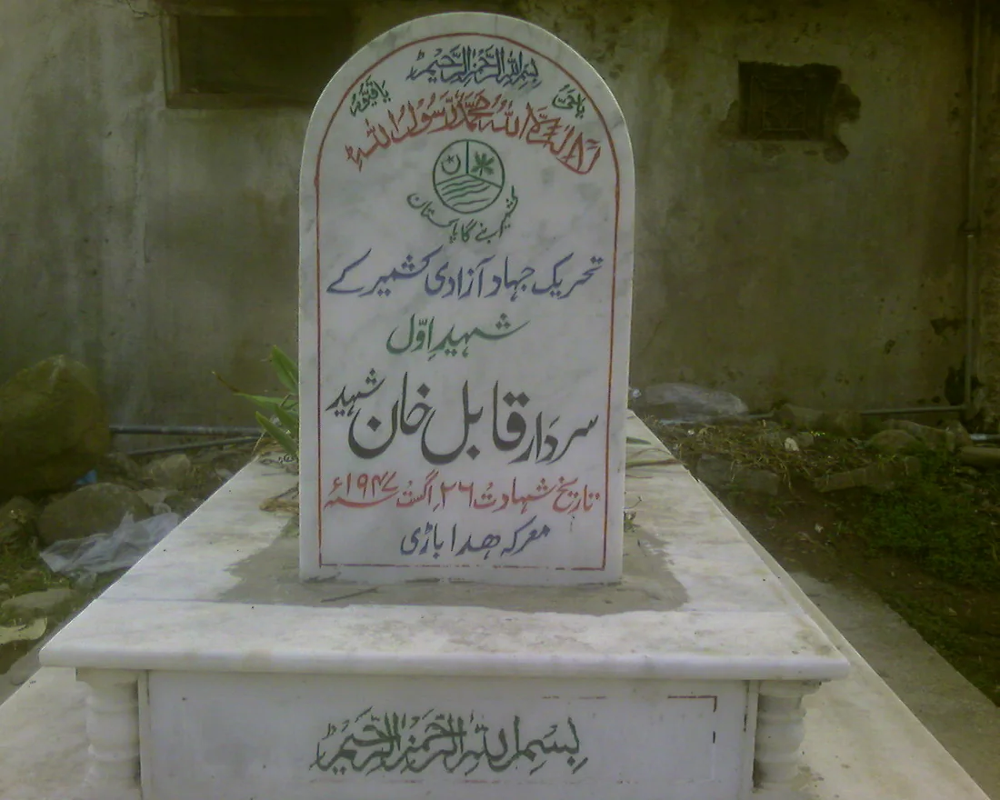 A photograph of a single white marble gravestone, inscribed in Urdu, in a martyrs' graveyard in Kashmir.