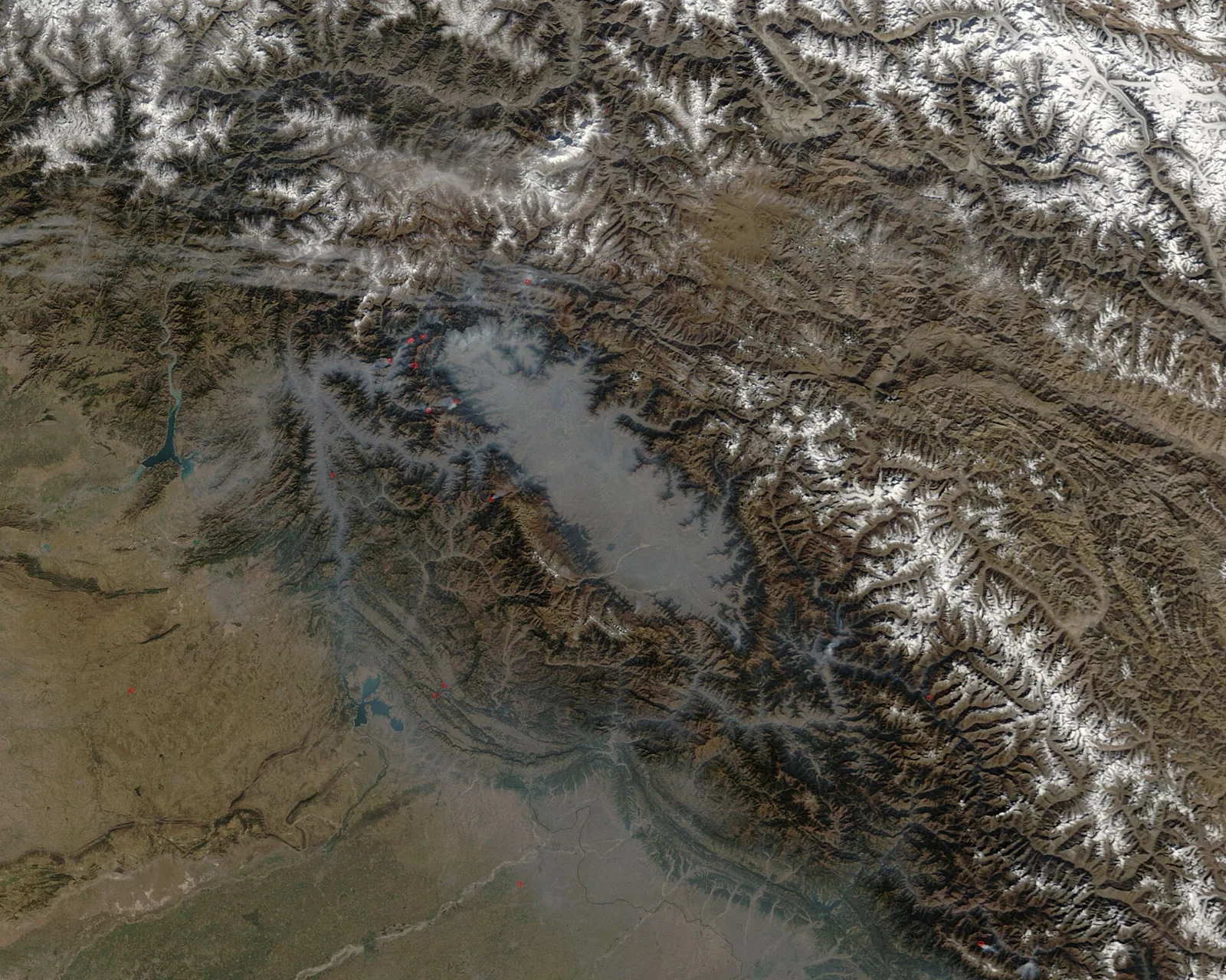 A satellite image of the Kashmir Valley, showing the valley floor enclosed by snow-covered mountain ranges, with Wular Lake visible as a dark shape.